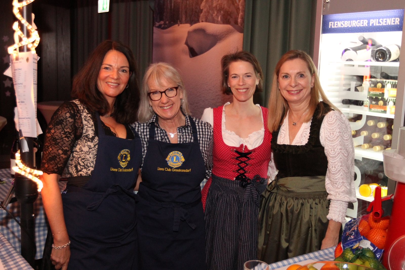 Vier Frauen in Schürzen und Dirndl am Getränkestand des Hüttenzaubers